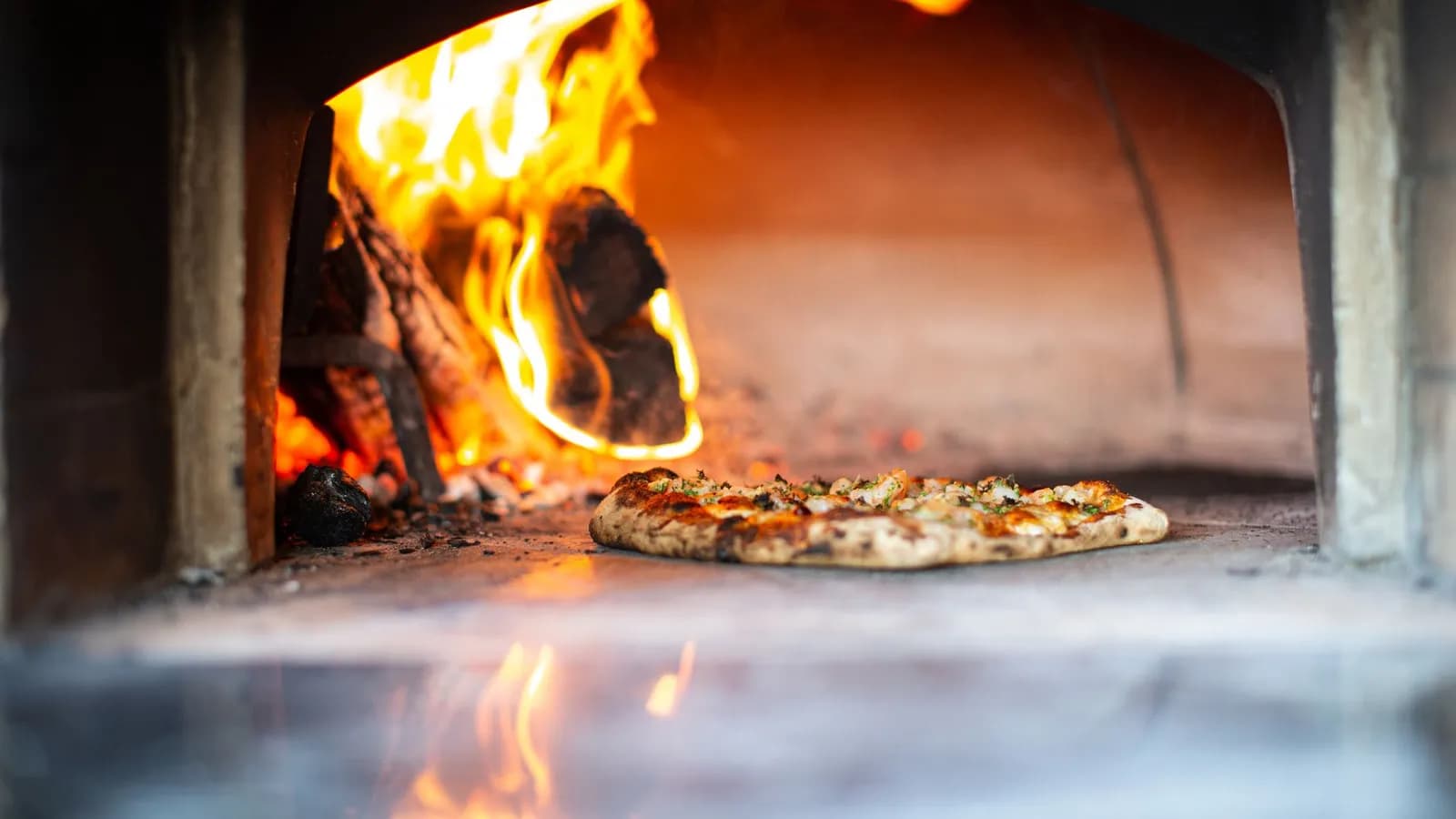 Vedfyrt pizzaovn med flammer i en italiensk trattoria